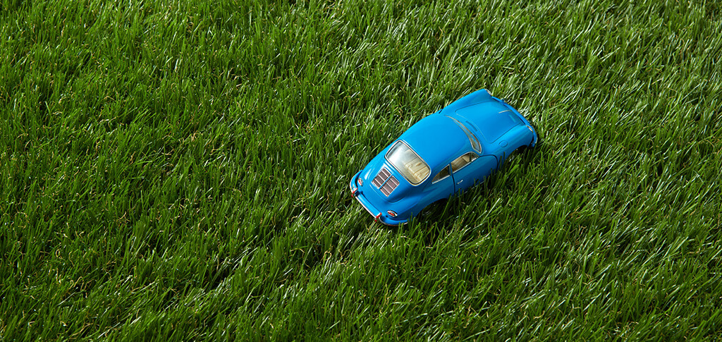 a blue child's toy car sits on artificial turf